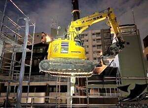 階上解体のために重機が吊り上げられている様子